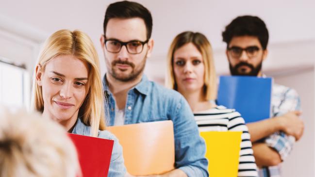 CAREERS: Group of young motivated people waiting in the line with a portfolio for a job interview.