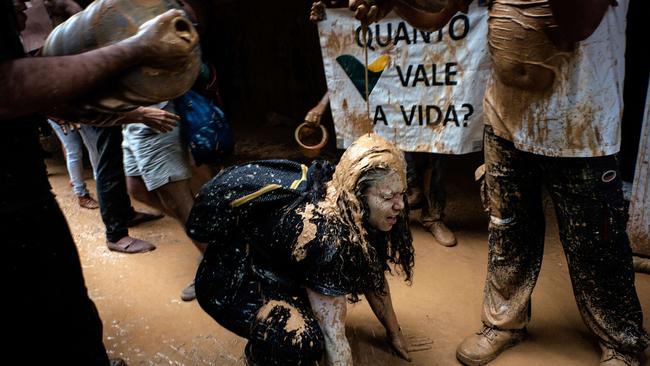 Protesters throw muddy water on the facade of Brazilian mining company Vale headquarters next to a sign reading "How much does a life cost?" in Rio de Janeiro. Picture: Yasuyoshi Chiba