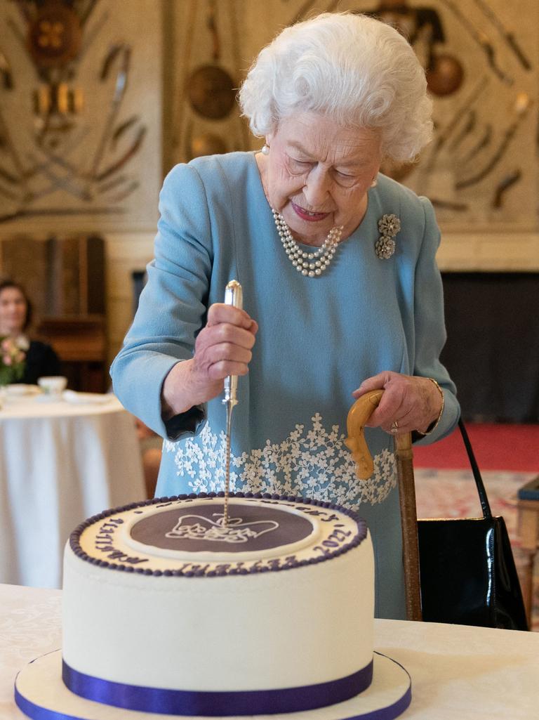 Britain's Queen Elizabeth II cuts a cake to celebrate the start of the Platinum Jubilee during a reception in the Ballroom of Sandringham House, the Queen's Norfolk residence on February 5, 2022. (Photo by Joe Giddens / POOL)