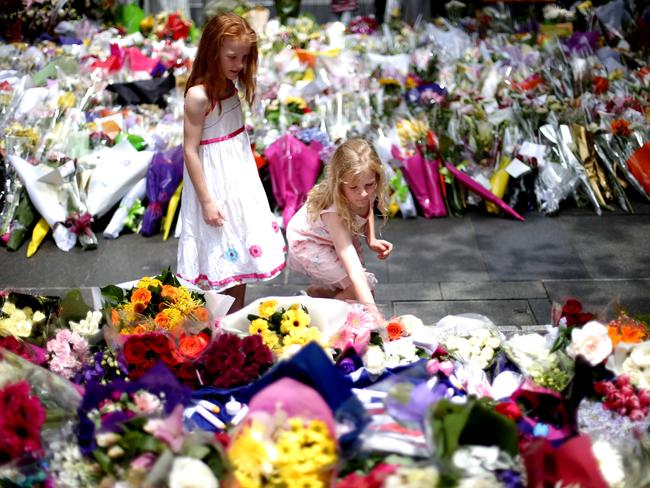 Children lay flowers at the scene of the Lindt cafe siege in Sydney’s CBD.