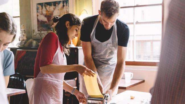 Students learn how to make pasta and use a pasta machine at a cooking class at Pasta Emilia in Surry Hills.