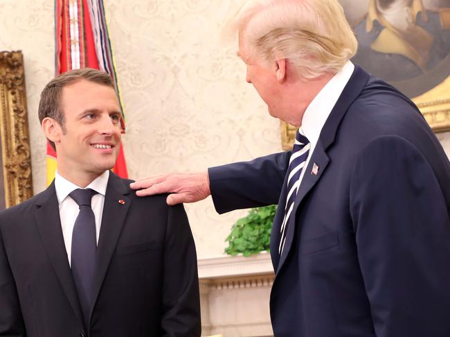 US President Donald Trump clears dandruff off French President Emmanuel Macron's jacket in the Oval Office. Picture: Ludovic Marin/AFP