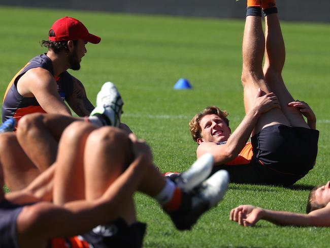 Lachie Whitfield (R) of GWS Giants stretches with team mates during a training session at the Giants Stadium at Sydney Olympic Park, Thursday, May 16, 2019.    (AAP Image/David Gray)