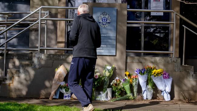 A man drops flowers outside the Boroondara Police station in Melbourne.