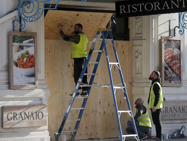 Workers board up the entrance of a restaurant in London. Picture: AP