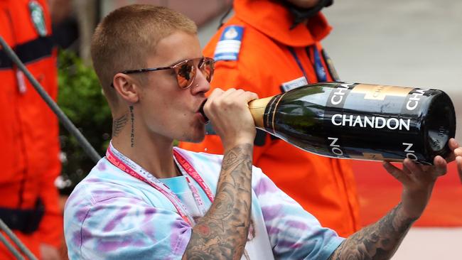 Justin Bieber drinks champagne at the podium during the Monaco Formula One Grand Prix.