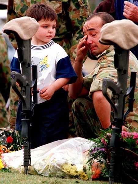 The son of one of the soldiers killed in the Blackhawk disaster looks on as his dad's best mate weeps after the memorial service for the soldiers in 1996. Picture Scott Radford-Chisholm