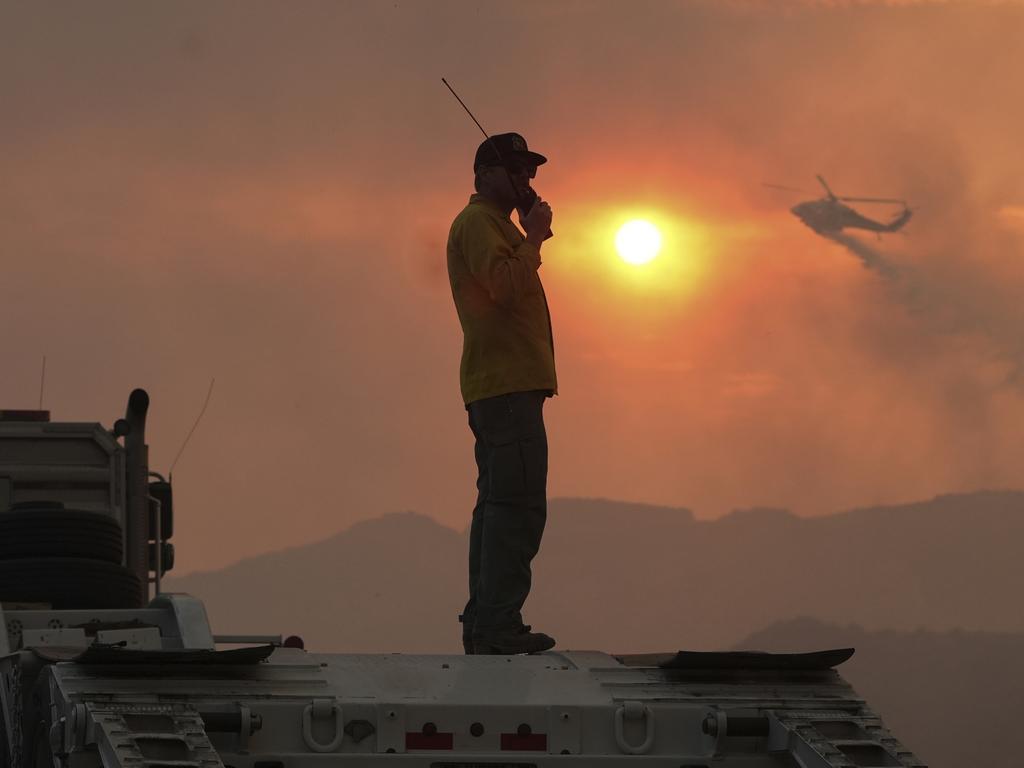 A firefighter monitors as a helicopter drops water on the Hughes Fire in Castaic, California. Picture: AP