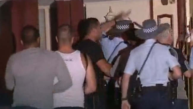 Angry bikies rush past police into a house on Rosecombe Place, Parafield Gardens, in November 2012 after a molotov cocktail was thrown inside during several days of escalating violence between Finks and Hells Angels.