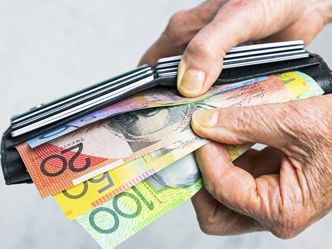 Close-up, senior female hands taking Australian banknotes (cash, currency) from purse containing many credit cards.  Horizontal, studio, copy space. Money generic