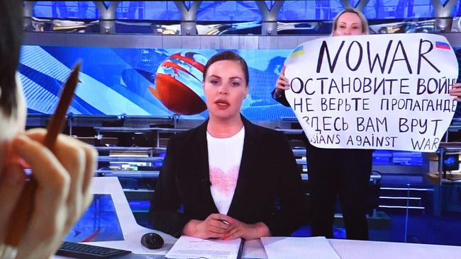 A woman looks at a computer screen watching a dissenting Russian Channel One employee entering Ostankino on-air TV studio during Russia's most-watched evening news broadcast. Picture: AFP