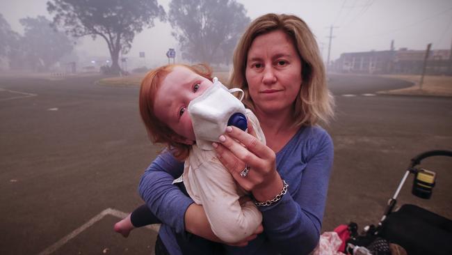 Mum Laura Langmead tries to put a breathing mask over her distraught daughter Evie, 1, to help filter the smoke. Picture: David Caird