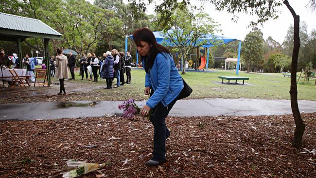 A woman places flowers on the ground. Picture: Adam Yip