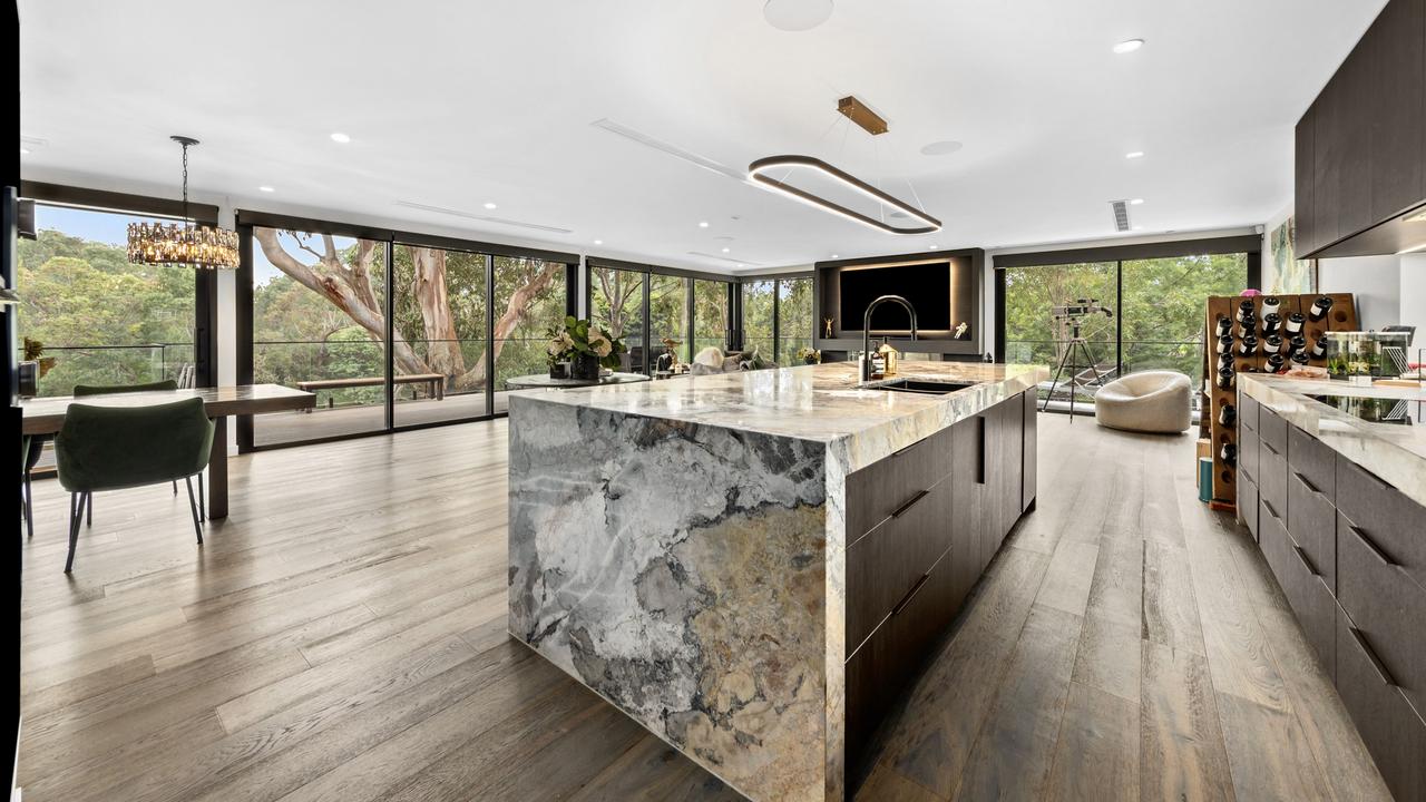 The slick kitchen and dining space sits among the trees.