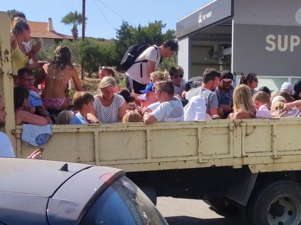 Tourists sit in the back of an open air lorry as they are evacuated during wildfires on the Greek island of Rhodes. Picture: AFP