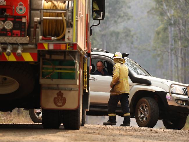 Firefighters are seen talking to local residents near a bushfire burning in Busbys Flat, northern NSW, Wednesday, October 9, 2019. (AAP Image/Jason O'Brien)