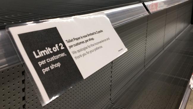 Signage for product limits on an empty toilet paper shelf in a Woolworths Supermarket in Melbourne on Friday. Picture: James Ross/AAP