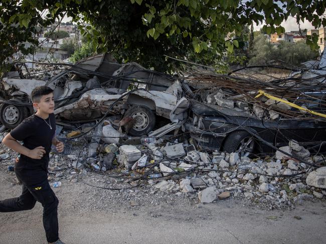 A boy runs past cars destroyed in a recent Israeli strike. Picture: Getty Images