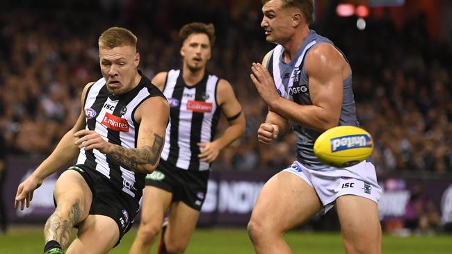 Jordan de Goey of the Magpies (left) kicks under pressure from Ollie Wines of the Power. Picture: AAP Image/Julian Smith