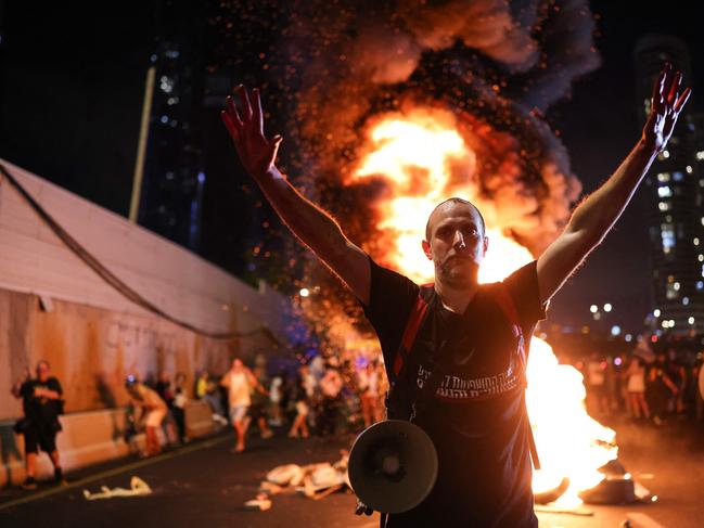 A man raises his arms in front of burning wooden pallets as protesters block Tel Aviv's Ayalon highway. Picture: AFP