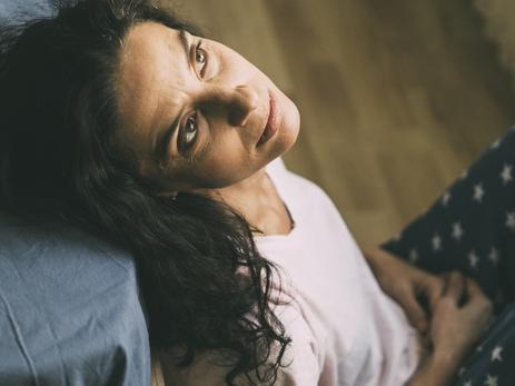 Mid age woman having problems sitting in her bedroom