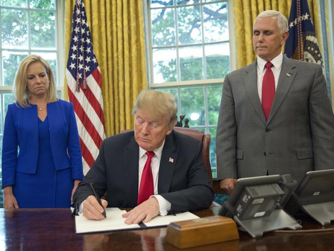 President Donald Trump signs an executive order to end family separations, during an event in the Oval Office of the White House in Washington, Wednesday, June 20, 2018. Standing behind Trump are Homeland Security Secretary Kirstjen Nielsen, left, and Vice President Mike Pence. (AP Photo/Pablo Martinez Monsivais)