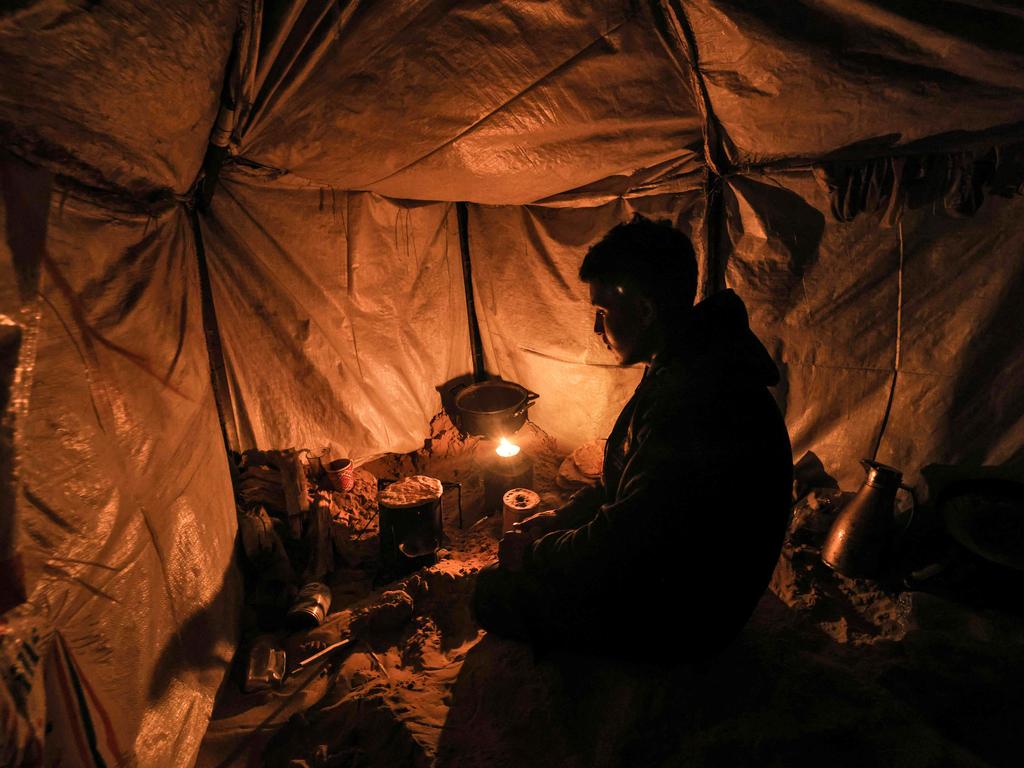 A displaced Palestinian makes flatbread in his tent near Rafah, marking 100 days of conflict between Israel and Hamas. Picture: AFP