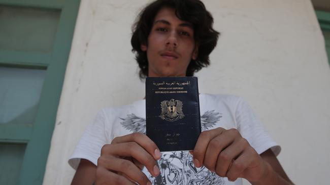 Syrian refugee Mouradin, 16, holds his Syrian passport, as he waits to be registered outside the local coast guard building in the Greek island of Leros. (AP Photo/Lefteris Pitarakis)