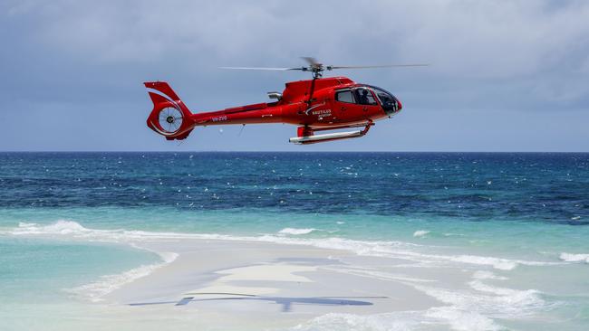 A Nautilus helicopter flies over Vlassof Kay on the Great Barrier Reef off Cairns. Picture by Sean Davey.