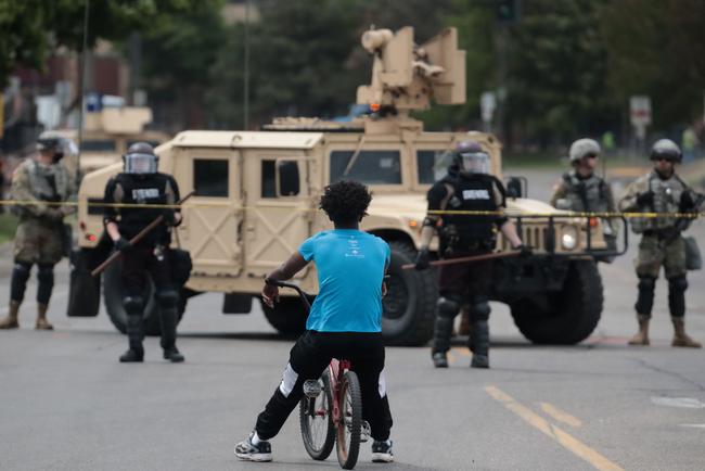 A man on a bicycle watches as law enforcement officials set up a road bloke in Minneapolis. Picture: AP