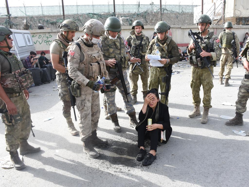 Turkish soldiers calm a woman down after she realised she lost her passport as people wait for evacuation at Hamid Karzai International Airport in Kabul. (Photo by Aykut Karadag/Anadolu Agency via Getty Images)