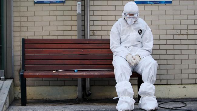 A medical worker wearing protective gear takes a rest as he waits for ambulances carrying patients infected with the COVID-19 coronavirus at an entrance of a hospital in Daegu in South Korea. Picture: AFP