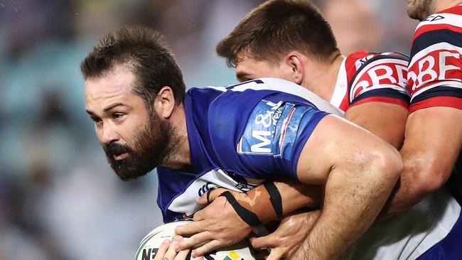 Aaron Woods of the Bulldogs is tackled by Roosters defence.