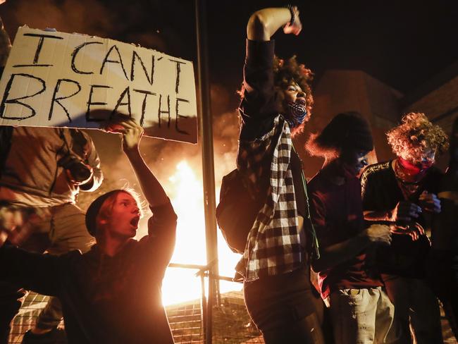 Protesters demonstrate outside of a burning Minneapolis police building. Picture: AP