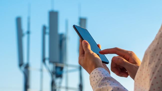 5G communications tower with man using mobile phone