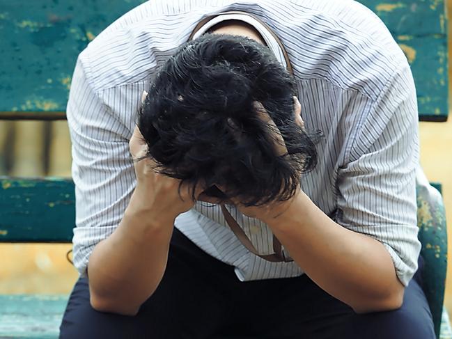 Frustrated stressed Asian business man with hand cover face sitting on the bench of public park and suffering from depression and exhausted worried man istock