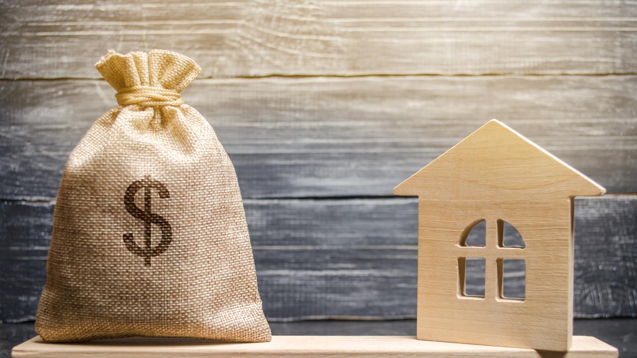 A money bag and a wooden house on the scales. The concept of real estate purchase. Sale of property. Payment of the mortgage. Redemption of taxes. Tax refund. Legacy / Inheritance tax concept; housing wealth balance generic