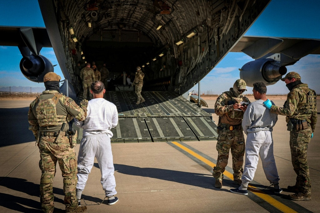 This handout photo released by the US Department of Homeland Security shows federal officials boarding detained migrants onto a flight to Guantanamo Bay Naval Base, from an undisclosed location in the United States