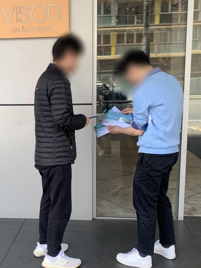 Two people with a wad of ballot papers outside the Vision Apartment building. Picture: Supplied