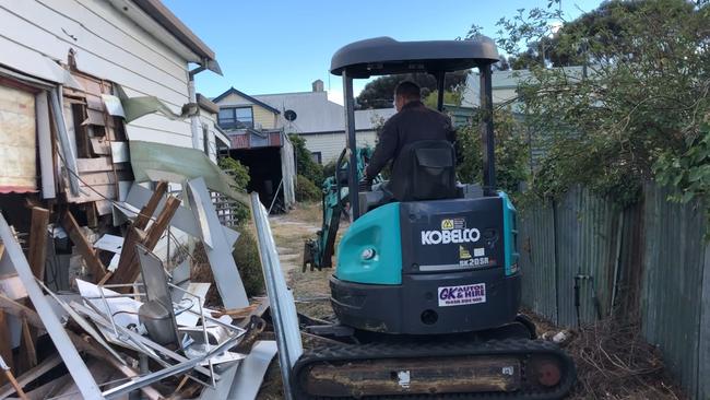 The pair filmed themselves on a hired excavator, ripping out the fireplace and pulling down the walls. Picture: Supplied.