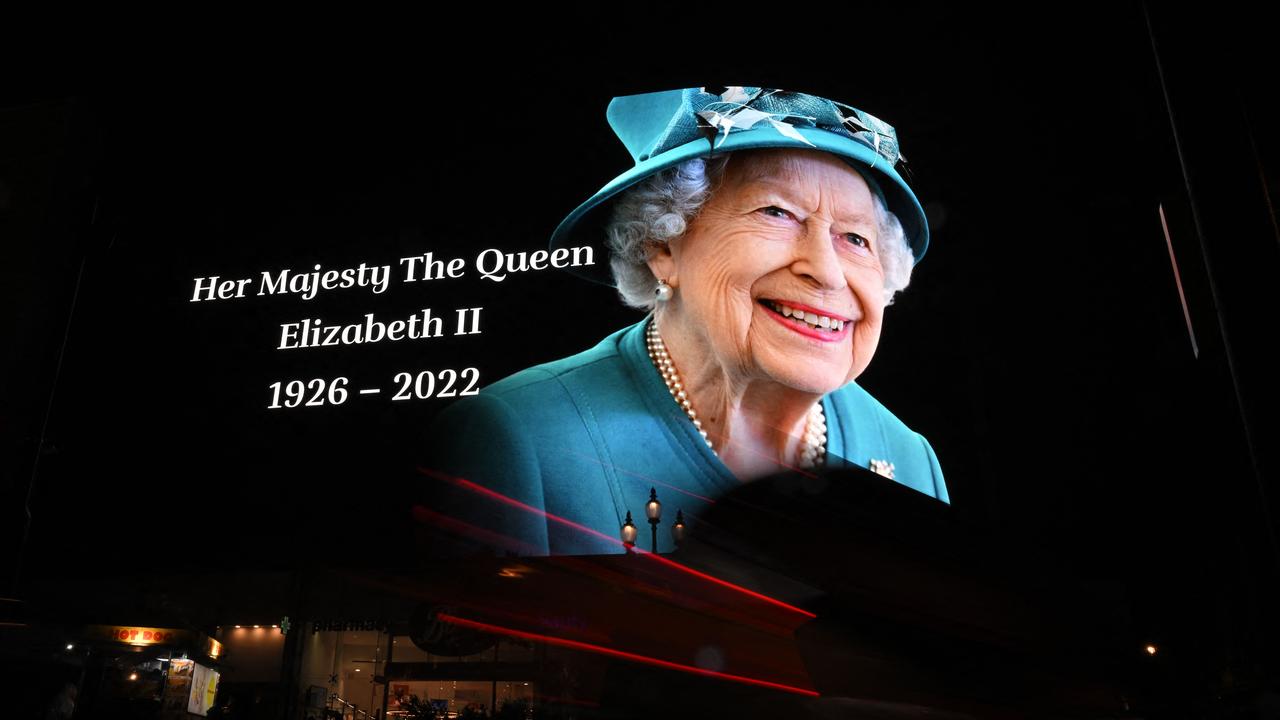 Members of the public stop in the rain to study a huge picture of Britain's Queen Elizabeth II displayed at Piccadilly Circus in central London. Picture: Ben Stansall / AFP