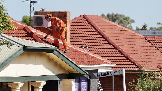 An SES worker searches a rooftop for evidence. Picture: AAP / Mike Burton