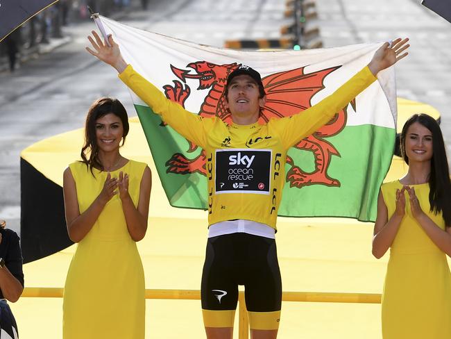 Tour de France winner Britain's Geraint Thomas, wearing the overall leader's yellow jersey, and draped in the flag of Wales celebrates on the podium after the twenty-first stage of the Tour de France cycling race over 116 kilometers (72.1 miles) with start in Houilles and finish on Champs-Elysees avenue in Paris, France, Sunday July 29, 2018. (Stephane Mantey, pool via AP)