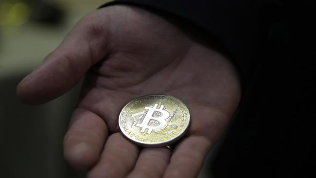 A visitor holds a virtual bitcoin during a webinar by Russian businessman German Sterligov in Moscow. Picture: Maxim Shipenkov