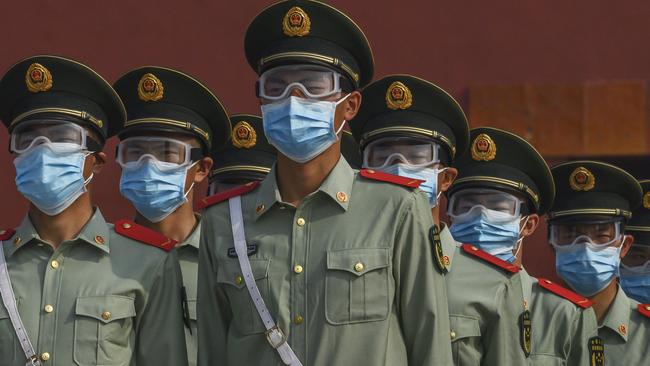 Chinese paramilitary police wear protective masks as they guard the entrance to Beijing’s Forbidden City. Picture: Getty Images