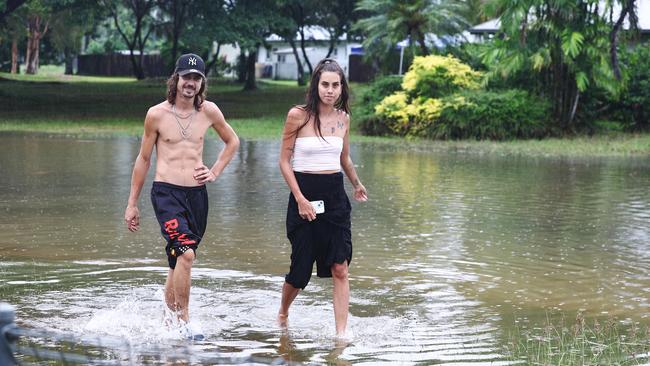 Klarwein Close residents Chantelle Villain and Jack Stirling walk through flood water at the end of his street, after heavy rain caused flooding to some areas in Gordonvale, south of Cairns in Far North Queensland. Picture: Brendan Radke