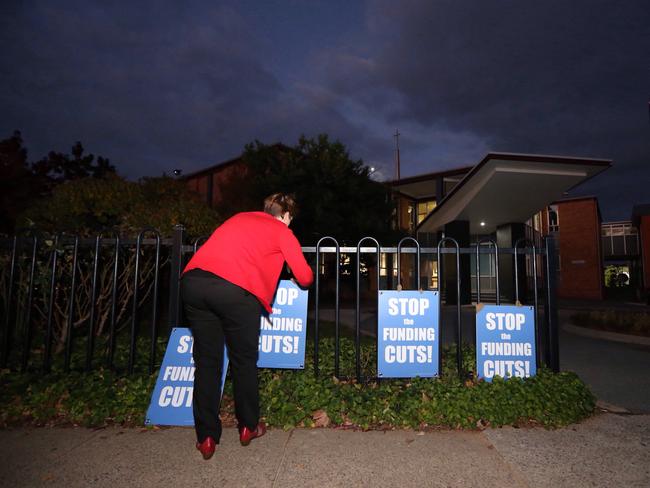 Staff erect posters on the outside of the school at a public meeting for all Catholic school parents, teachers to discuss the Government’s funding cut to Catholic schools in the ACT.  Picture Gary Ramage