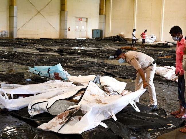 A policeman helps a man to identify his family member's body at a business park used as temporary mortuary for the dead recovered from the carriage wreckage. Picture: AFP