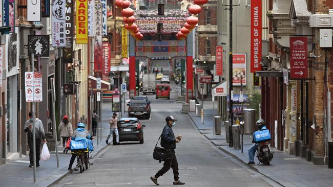 A man wearing a face mask crosses a quiet road in Melbourne's Chinatown during the week. Picture: AFP