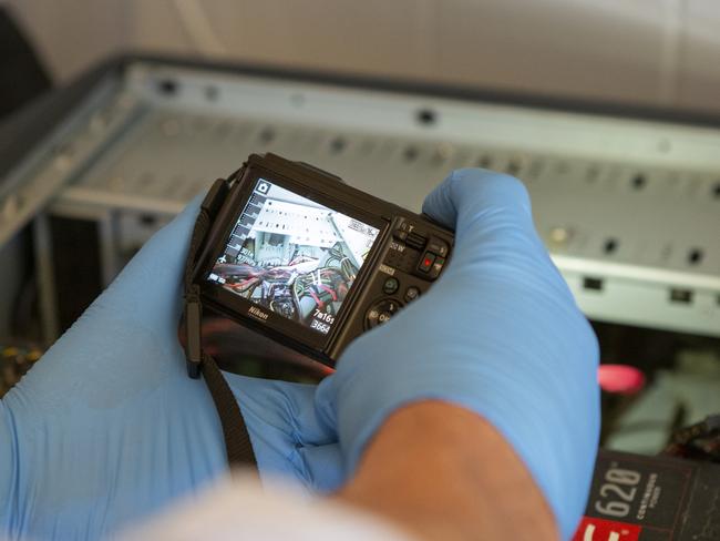 Police gather evidence during a raid targeting hackers. Picture: AFP.